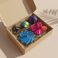 Kit Exploração Sensorial Sensoria em caixa kraft aberta com papel ondulado — inclui Estrela Sensorial azul, Bloom Sensorial rosa, Órbita Flow roxa, Cubo Loop azul e amarelo e Cubo Origami Infinito colorido em impressão 3D